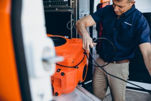 water damage restoration technician takes equipment out of van